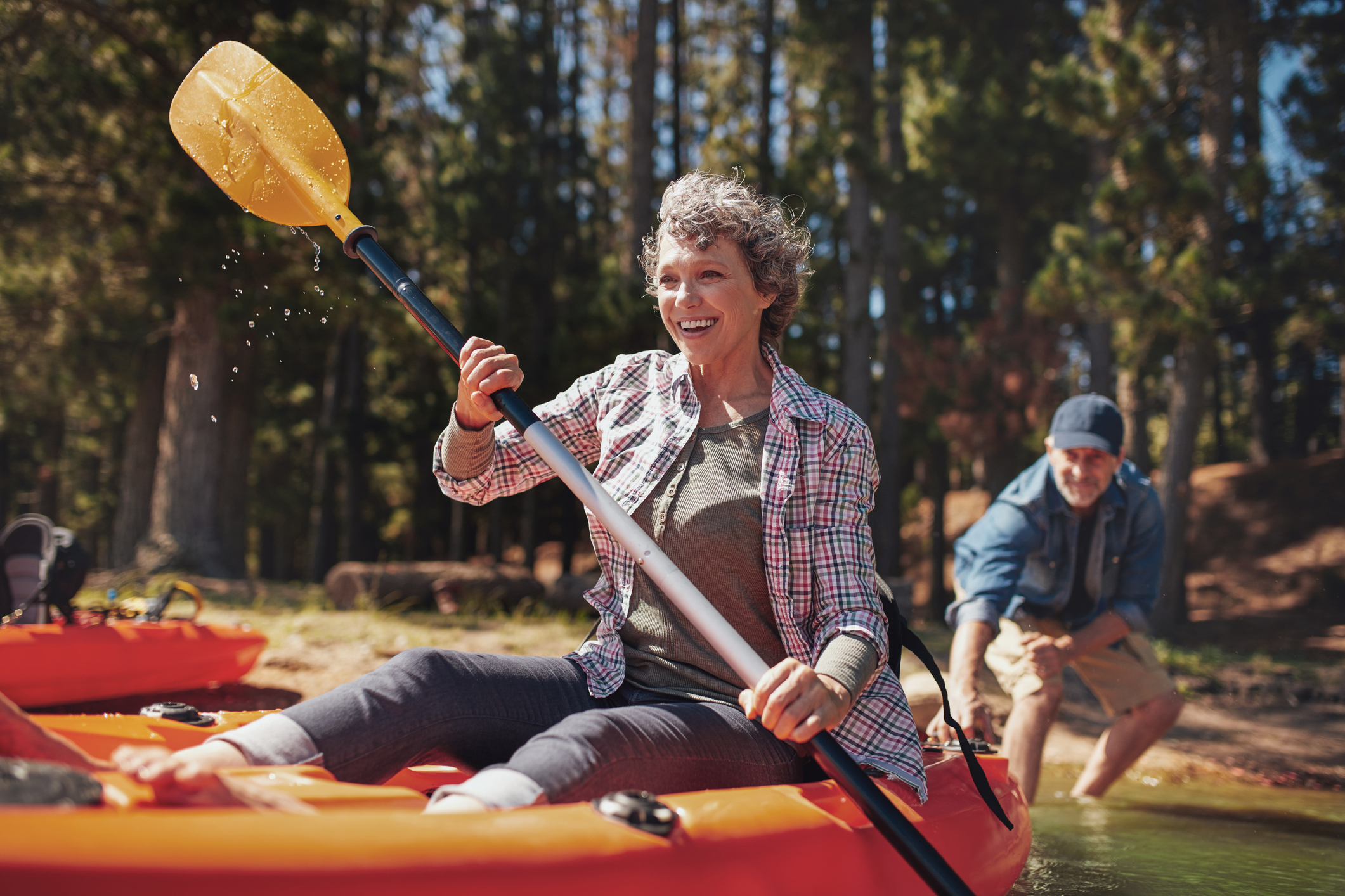 A retired couple paddleboarding on a calm mountain lake